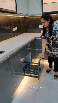 a woman standing in front of an open dishwasher with her hand on the door