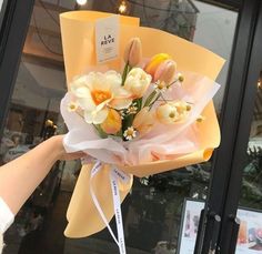 a bouquet of tulips and daffodils is being held by a woman's hand