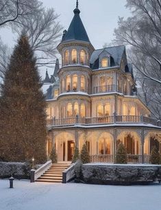 a large victorian style house lit up at night in the snow with trees and bushes