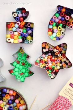 several cookie cutters with different colored beads and christmas tree shapes on the table next to each other