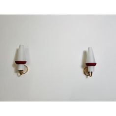 two white and red wall lights mounted on the side of a wall