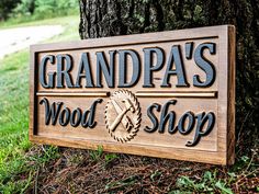 a wooden sign that says grandpa's wood shop next to a tree