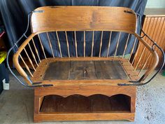 an old wooden bench with metal bars on the seat and back rests against a black backdrop