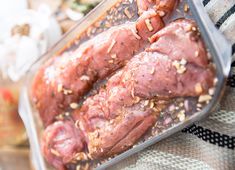 raw meat in a plastic container sitting on a table cloth next to other food items