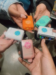 four people holding small cell phones in their hands