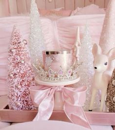 a pink princess themed table setting with white and pink trees, deer figurines and a tiara