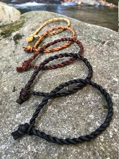 three braided bracelets sitting on top of a rock