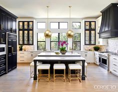 a large kitchen with black cabinets and white counter tops, along with an island in the middle