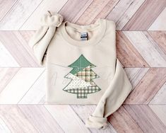 a white sweater with a green christmas tree on the front and plaid trees on the back