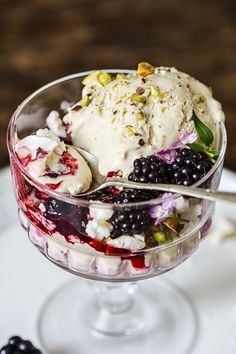 an ice cream sundae with berries and pistachios in a glass bowl