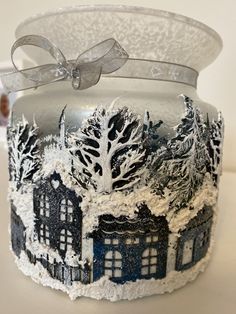 a frosted glass jar decorated with houses and trees