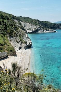 a train traveling along the side of a mountain next to a blue body of water