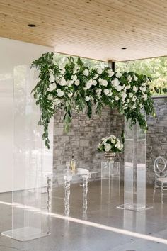 an arrangement of white flowers and greenery in clear acrylic vases on a table