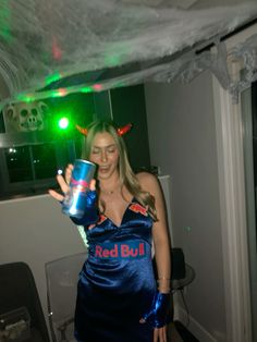 a woman in a blue dress holding up a cup with red bull written on it