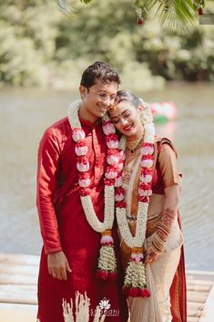 a man and woman standing next to each other in front of a body of water