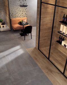 an empty room with shelves and bottles on the wall, next to a small table