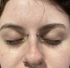 a close up of a person with eyeliners and nose piercing on their forehead