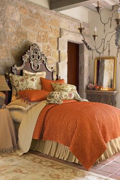 a bed with an orange bedspread in a bedroom next to a chandelier