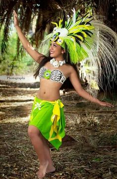 a woman in a green skirt and headdress is dancing with her arms out