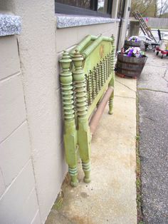 a green bench sitting on the side of a building