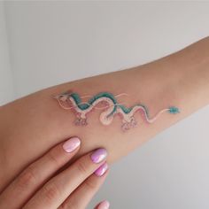 a woman's arm with a dragon tattoo on the left side of her arm