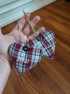 a hand holding two heart shaped ornaments with the letter u on them, hanging from twine