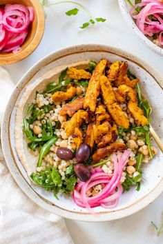 a salad with chicken, beans and greens in a white bowl on a marble table