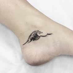 a small tattoo on the foot of a woman's feet, with a wave coming out of it