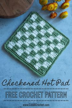 a green and white crocheted pot holder sitting on top of a blue surface