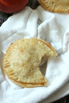 two apple pies sitting on top of a white napkin next to an apple slice