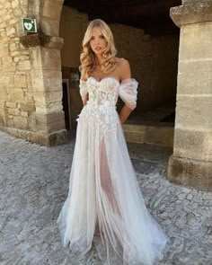 a woman in a white wedding dress posing for the camera with her hands on her hips