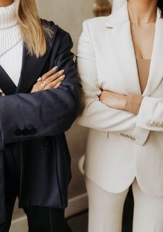 two women standing next to each other with their arms crossed