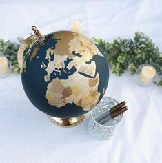 a blue and gold globe sitting on top of a table next to two tea lights