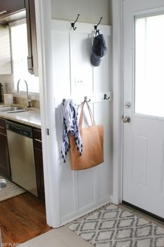 an open door with a purse hanging on the wall next to a sink and dishwasher