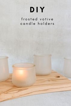 three white votive candles sitting on top of a wooden board with text overlay that reads diy frosted votive candle holders