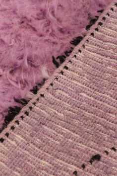 a close up view of a purple rug with some black dots on the bottom and side