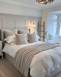 a bed with white sheets and pillows in a bedroom