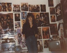 a woman standing in front of a wall full of pictures and posters on the wall