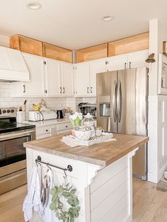 a kitchen with white cabinets and stainless steel appliances, including a large island in the center