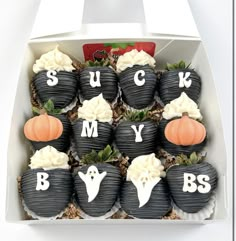 cupcakes decorated with black and white frosting are arranged in a halloween themed box