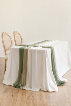 a table with two chairs and a white table cloth on it in front of a wall