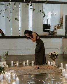 a woman kneeling down in front of candles