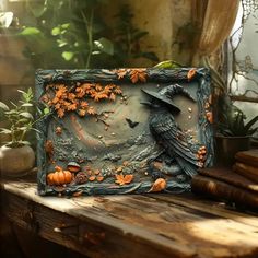 a black bird sitting on top of a wooden table next to some pumpkins and leaves