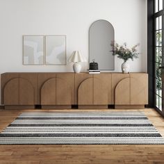 a living room with a rug, mirror and vases on the sideboard in front of it