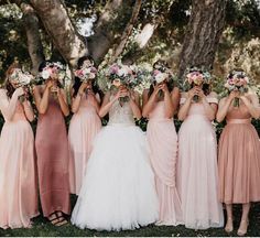 a group of women standing next to each other holding flowers in front of their faces