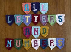 crocheted letters and numbers are arranged on a wooden surface with the words all letters and numbers spelled out