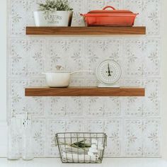 two wooden shelves with pots and pans sitting on top of them, in front of a wallpapered background