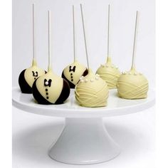 chocolate covered cake pops with white frosting and black bow tie decorations on a plate