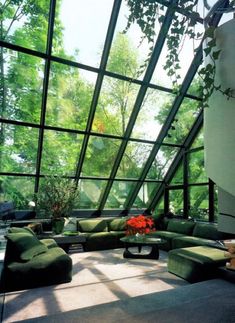 a living room filled with lots of furniture under a large glass ceiling covered in greenery