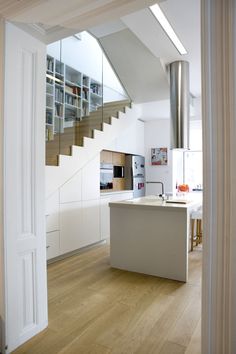 an open kitchen and living room area with stairs leading up to the upper floor in this modern home